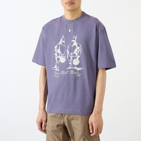 Model wearing Emporium Armour Logo T-Shirt in burgundy with white screen-print graphic, styled with khaki trousers and a chain necklace.