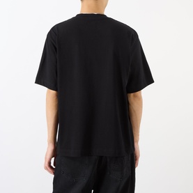 Model wearing Emporium black cotton T-shirt, rear view, oversized fit with dropped shoulders, paired with dark trousers.