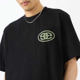 Model wearing Emporium black cotton T-shirt with green oval logo graphic on chest, styled with a silver chain necklace.