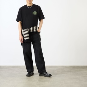 Model wearing Emporium black cotton T-shirt with logo print, styled with striped jacket tied at waist and black cargo trousers.
