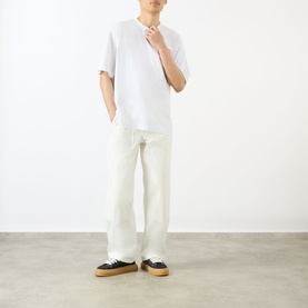 Model wearing Emporium EE Logo T-Shirt in white with crew neck and dropped shoulders, styled with cream wide-leg trousers and black trainers.
