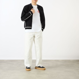 Model wearing Emporium EE Logo T-Shirt in white with black bomber jacket, white trousers and navy low-top trainers.