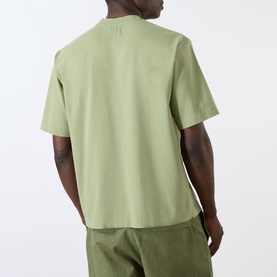 Model wearing Emporium EE Logo T-Shirt in khaki, rear view, showing dropped shoulders and straight hemline, styled with matching khaki trousers.
