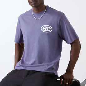 Model wearing Emporium burgundy cotton T-shirt with chest logo graphic, styled with black trousers and silver chain necklace.