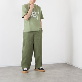 Model wearing Emporium Lucky Stars Logo T-Shirt in khaki green, boxy fit, with matching khaki wide-leg trousers and platform sandals.