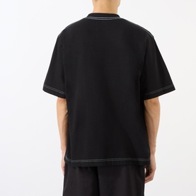 Model wearing Emporium Script Logo T-Shirt in black, rear view showing contrast white stitching detail, styled with matching black trousers.