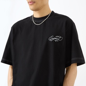 Model wearing Emporium Script Logo T-Shirt in black with embroidered logo and contrast stitching, styled with a silver chain necklace.