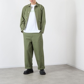 Model wearing Emporium There'll Be Signs Logo T-Shirt in white, styled with olive green jacket and wide-leg trousers, black chunky shoes.