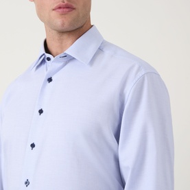 Model wearing Eterna blue cotton formal shirt with navy contrast buttons and spread collar, close-up detail view
