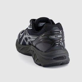 Asics trainer in black with silver logo detailing, chunky black rubber sole, shown from rear three-quarter angle.