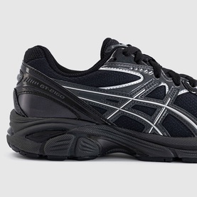 Asics GT-2160 trainers in black with silver logo detailing, black laces, and chunky black sole, close-up angled view