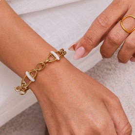Model with Mettle & Bloom gold chain bracelet featuring crystal-encrusted rectangular clasp detail, styled with a gold ring