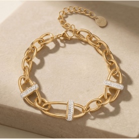 Mettle & Bloom gold chain-link bracelet with crystal-pav&eacute; oval connectors and extender chain, on stone surface.