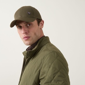 Model with Paul Smith Access Zebra Logo Cap in military green, curved visor, small zebra embroidery, worn with matching green quilted jacket.