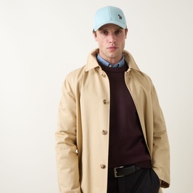 Model with Paul Smith Access Zebra Logo Cap in light blue, styled with a beige mac coat and burgundy knit jumper.
