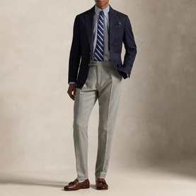 Model wearing navy blazer and grey trousers, styled with a blue striped tie, light blue shirt, and brown leather loafers
