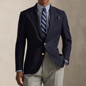 Model wearing navy blazer with gold buttons, styled with striped shirt, navy striped tie, pocket square and grey trousers