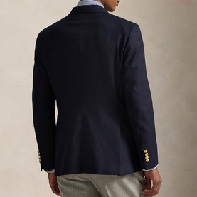 Model wearing navy blazer with gold buttons, rear view, styled with light blue shirt and grey trousers