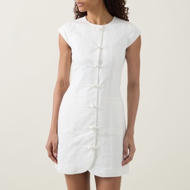 Model wearing Aligne Jennie Shirt Dress in white, featuring knot front fastenings, cap sleeves, round neck, and mini length.