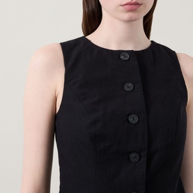Model wearing Aligne Leah Mini Dress in black, showing round neckline, sleeveless cut and front button fastening detail in linen-blend fabric.