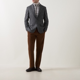 Model wearing Gant black grey pinstripe blazer with check shirt and brown trousers, hands in pockets, dark leather shoes.