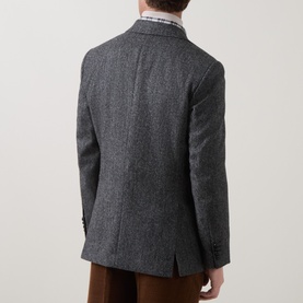Model wearing Gant black grey blazer, back view, showing centre vent and checked shirt collar detail, styled with tan trousers