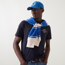 Model with Gant Monogram Moleskin Cap in Nautical Blue, curved visor with collegiate logo, styled with navy tee and blue stripe scarf