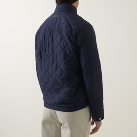 Model wearing Gant Evening Blue quilted casual jacket, rear view, styled with light beige trousers