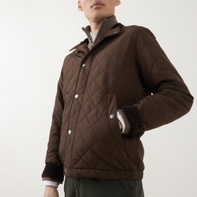 Model wearing Gant Classic Quilted Jacket in black brown, with funnel neck, snap buttons, and quilted texture, styled with dark trousers.