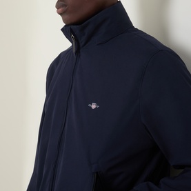 Model wearing Gant Hampshire Shield Logo Jacket in Evening Blue, showing stand collar, front zip fastening and chest Shield logo detail.
