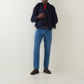 Model wearing Gant Hampshire Shield Logo Jacket in Evening Blue with blue jeans, red top, and brown shoes.