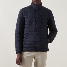 Model wearing Gant Evening Blue quilted down casual jacket with stand collar, snap buttons, and chest zip pocket, styled with beige trousers