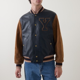 Model wearing Gant Varsity Logo Leather Bomber Jacket in navy, with tan suede sleeves, Y appliqu&eacute;, snap buttons, and ribbed trims. Styled with blue