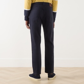 Model wearing Gant Evening Blue Casual Trousers, rear view, styled with yellow sweatshirt and navy trainers.