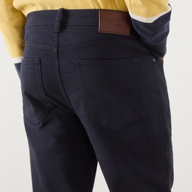 Model wearing Gant Evening Blue casual trousers, close-up of rear pockets with brown leather patch detail, styled with yellow top.