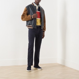 Model wearing Gant Evening Blue Casual Trousers styled with a varsity jacket, colourblock polo, and dark trainers.