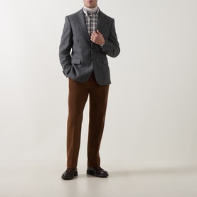 Model wearing Gant Mahogany Brown wool casual trousers, styled with a grey herringbone blazer, check shirt and black loafers.