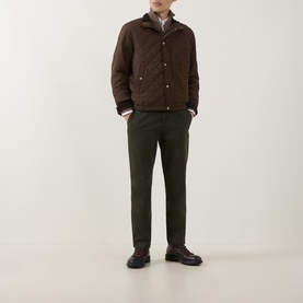 Model wearing Gant Dark Moss Green chinos with dark brown quilted jacket and brown leather shoes.