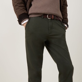 Model wearing Gant dark moss green cotton chino trousers with brown belt, styled with stripe shirt and brown knit sweater.