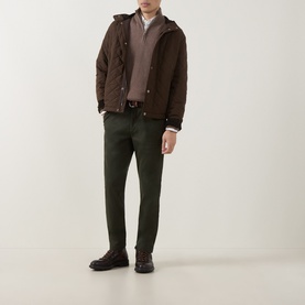 Model wearing Gant Dark Moss Green slim chino trousers, styled with dark brown quilted jacket and leather loafers.
