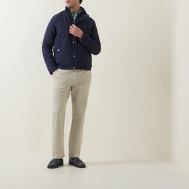 Model wearing Gant Classic Mid-Rise Straight Leg Chinos in clay beige, styled with a navy quilted jacket and dark loafers.
