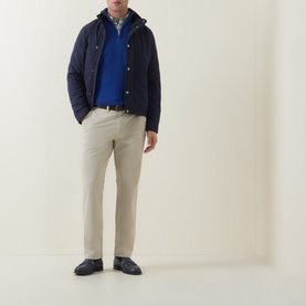 Model wearing Gant Classic Mid-Rise Straight Leg Chinos in clay beige, styled with a navy quilted jacket and blue knit jumper.