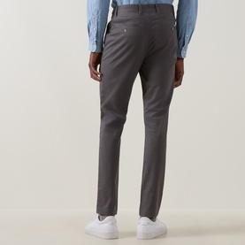 Model wearing Gant Dusky Anthracite slim-fit cotton chinos, rear view, styled with a light blue shirt and white trainers.