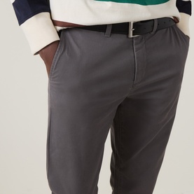 Model wearing Gant Dusky Anthracite slim chino trousers with brown leather belt, styled with a striped cotton top.