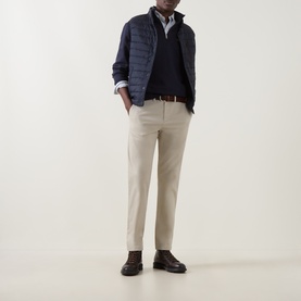 Model wearing Gant Clay Beige Chinos styled with a navy gilet, navy jumper, white shirt, brown belt and dark brown boots.