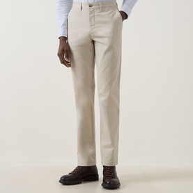 Model wearing Gant Clay Beige cotton chino trousers, styled with a light blue shirt and brown leather lace-up shoes.