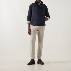 Model wearing Gant Clay Beige Chinos styled with a navy quilted gilet and white shirt, dark brown leather shoes.