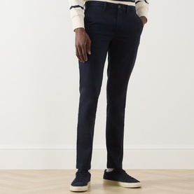 Model wearing Gant Evening Blue slim-fit chino trousers in cotton-elastane, styled with a cream shirt and navy trainers.