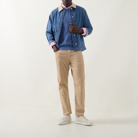 Model wearing Gant Shield Logo Cable-Knit Sweater in Blue Horizon, styled with a blue overshirt, tan trousers and white trainers.