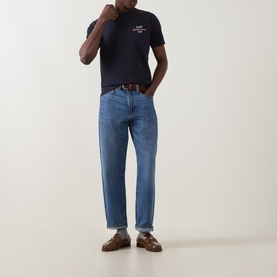 Model wearing Gant Evening Blue Crew Neck T-shirt with mid-wash blue jeans, brown belt and loafers.